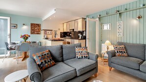 A modern living room with two grey sofas, a dining table, and a kitchen in the background. - St Mary's Seaview - In Town Walls, Close to Beach (Tenby)