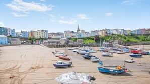 Un pueblo costero con edificios coloridos, una playa de arena y numerosos barcos amarrados.