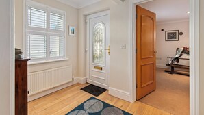 Un pasillo con una puerta de madera, un radiador y una ventana con persianas.
