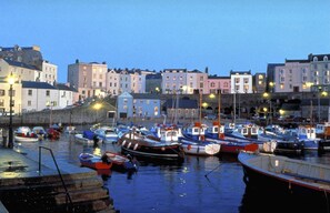A harbor with boats docked, buildings in the background, and a stone wall. - 1 Bed in Tenby (oc-25957) (Tenby)