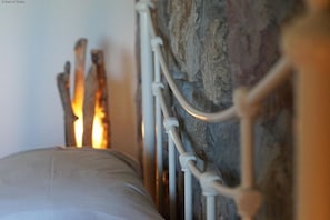 A bed with a white pillow against a stone wall and a metal headboard. - 9 Bed in Pwllheli (oc-387040) (Pwllheli)