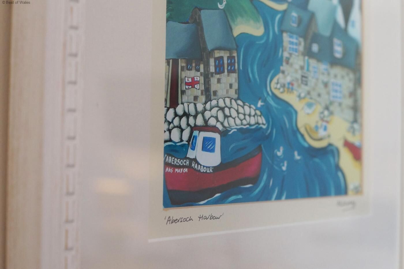 Ein gerahmtes Kunstwerk zeigt eine Hafenszene mit einem Boot, das 'Abersoch Harbour' genannt ist.