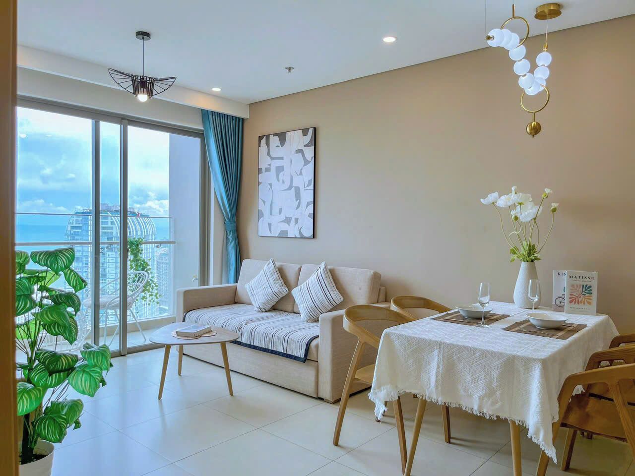 A modern living room with a sofa, dining table, and a view of the city through large windows.