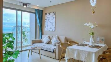 A modern living room with a sofa, dining table, and a view of the city through large windows.