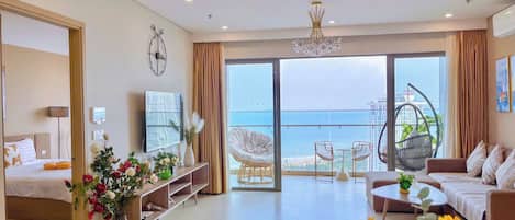 Una sala de estar moderna con sofá, mesa de centro y comedor. Hay un balcón con vista al mar.
