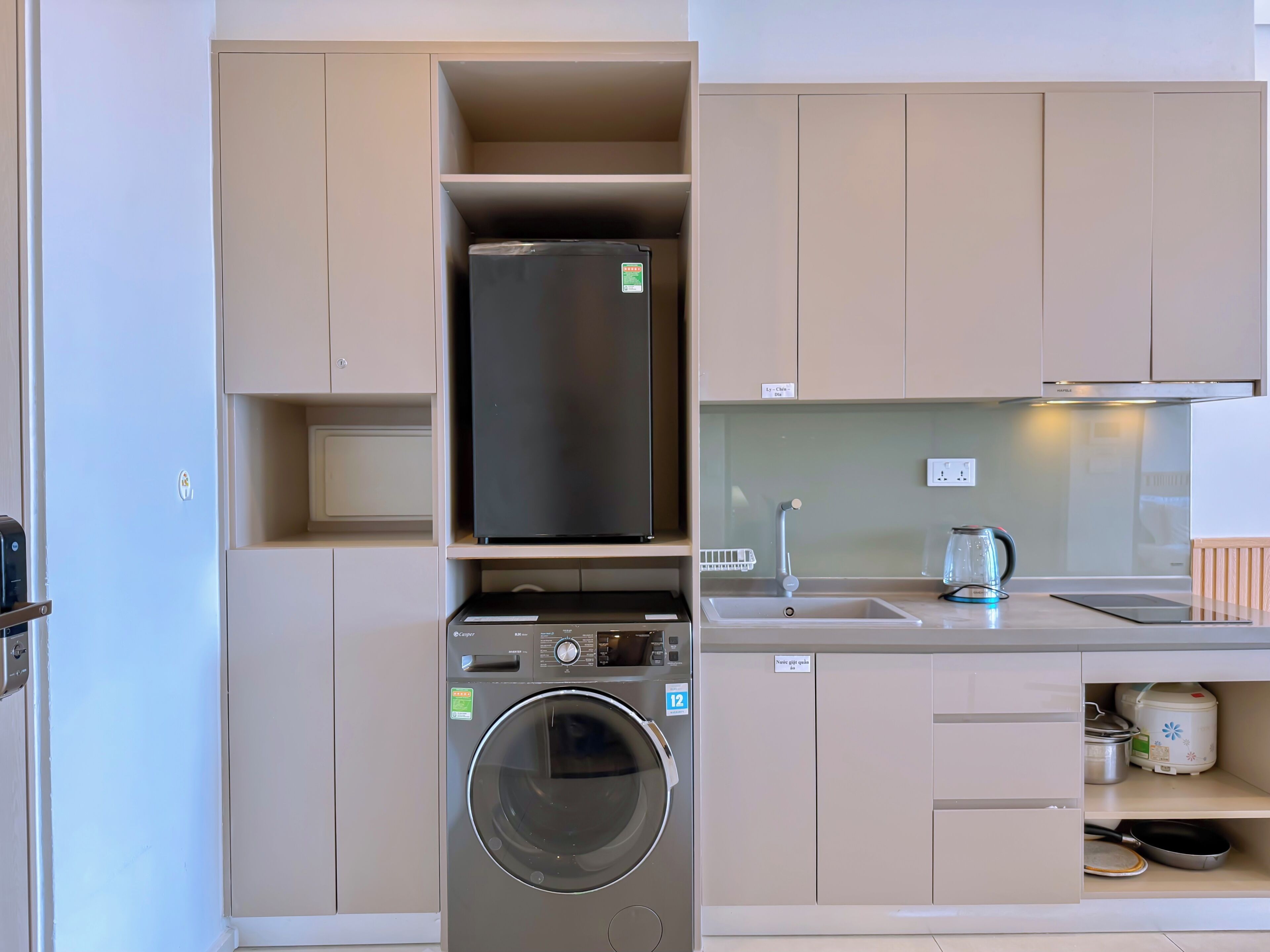 Eine kleine Küche mit Waschmaschine, Kühlschrank und Spüle.