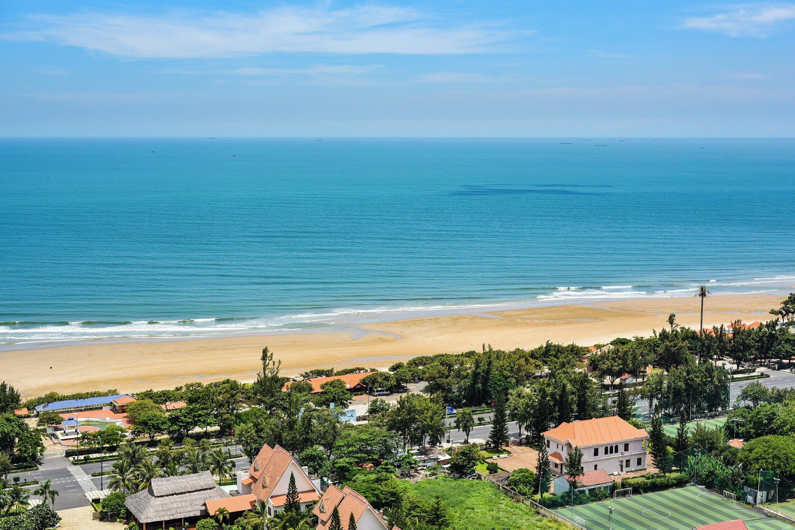 A coastal residential area with houses, a beach, and a clear view of the ocean.
