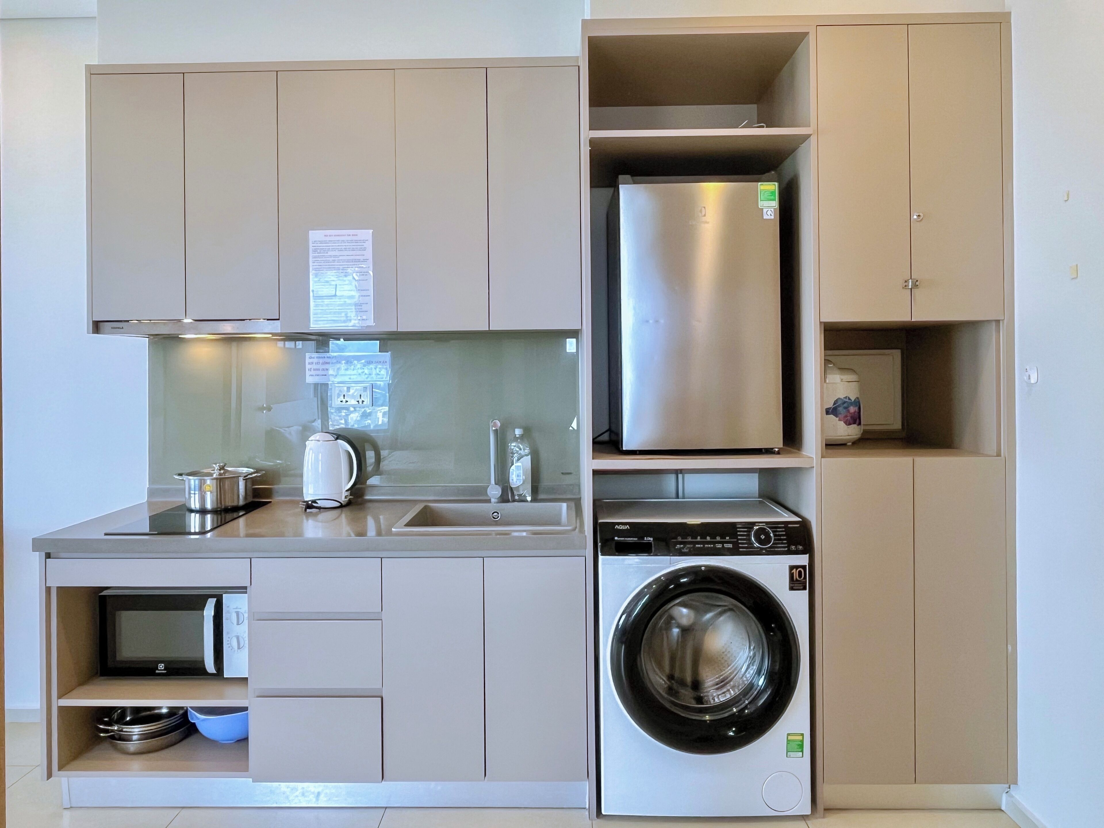A compact kitchen with a built-in washing machine, a microwave, and a refrigerator.