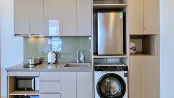 A compact kitchen with a built-in washing machine, a microwave, and a refrigerator.