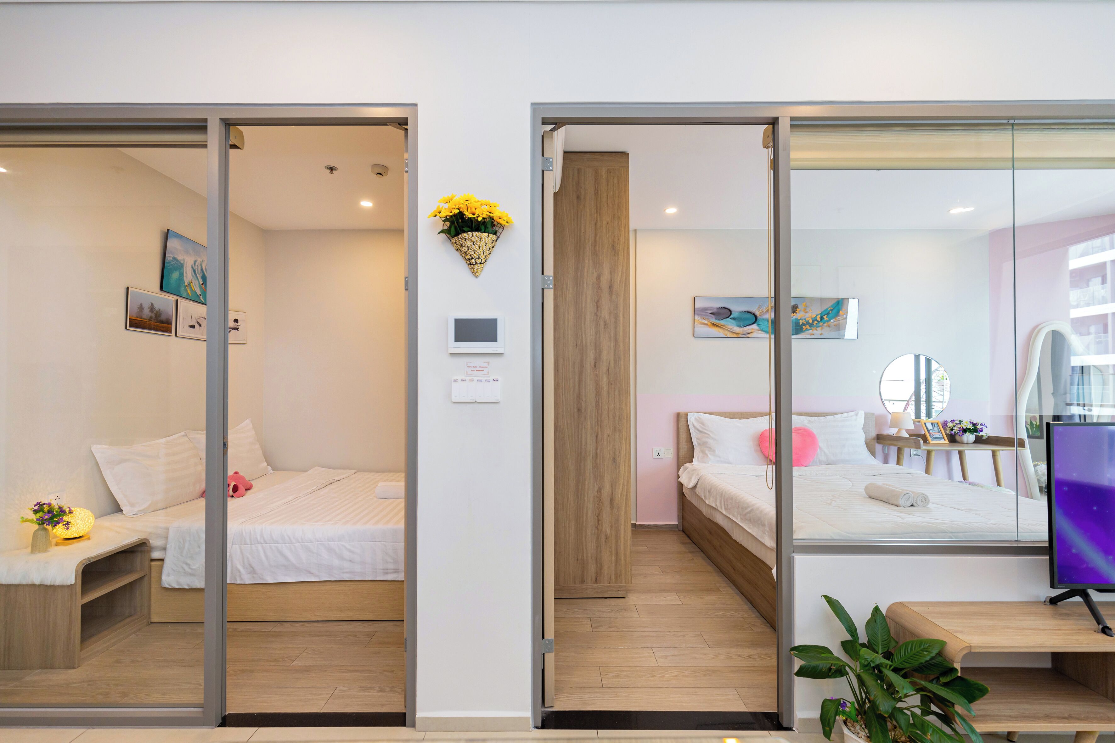 A modern hotel room with a bed, bedside table, and a small desk with a chair. There is a window with a view of the outside.