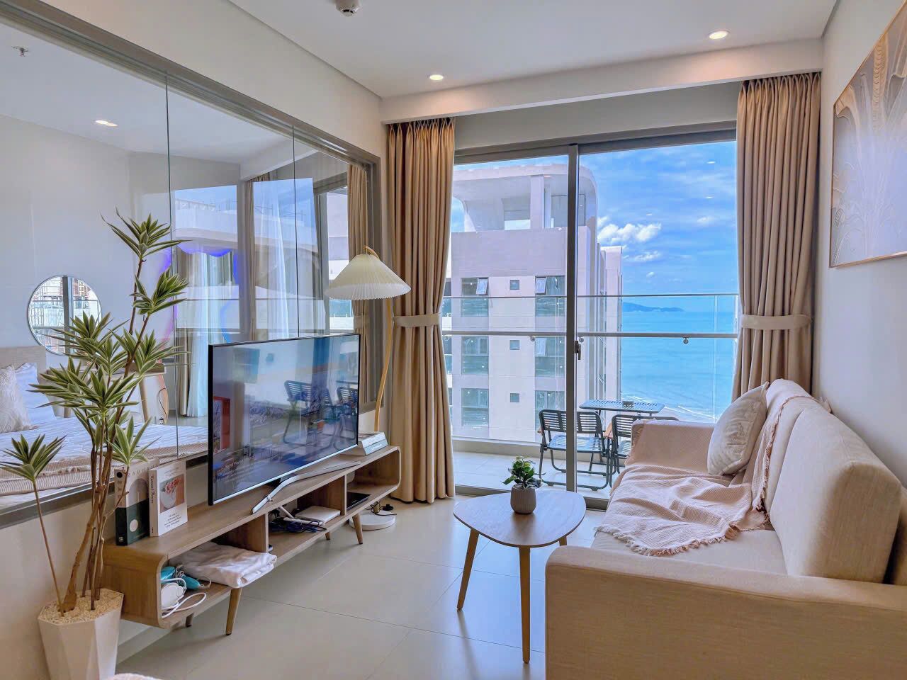 Una sala de estar moderna con un televisor de pantalla plana, un sofá, una mesa de centro y un balcón con vistas al mar.