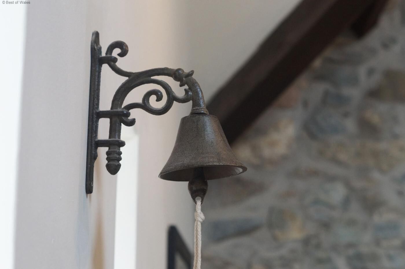 Campana penjada a la paret amb un suport decoratiu.
