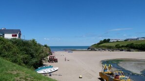 A beach with a tractor, a boat, and a lifeboat.
