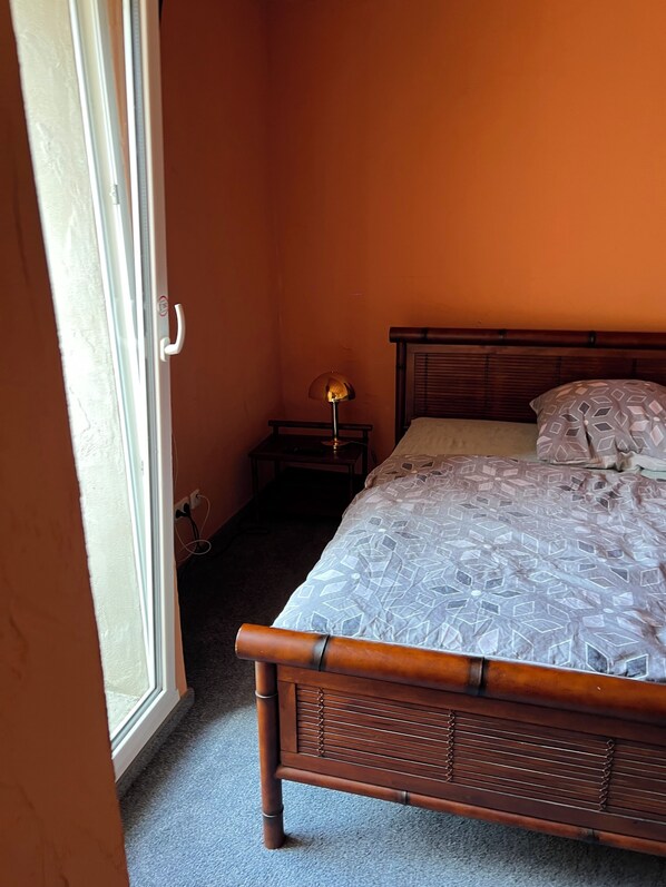 A bedroom with a bed, a nightstand, a lamp, and a window. - Villa Stern Apartment: Spacious with two separate bedrooms / Sleeps 4 (Nidderau)