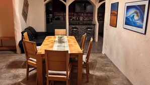 Een eetgedeelte met een houten tafel en stoelen, een kroonluchter en een keuken op de achtergrond.