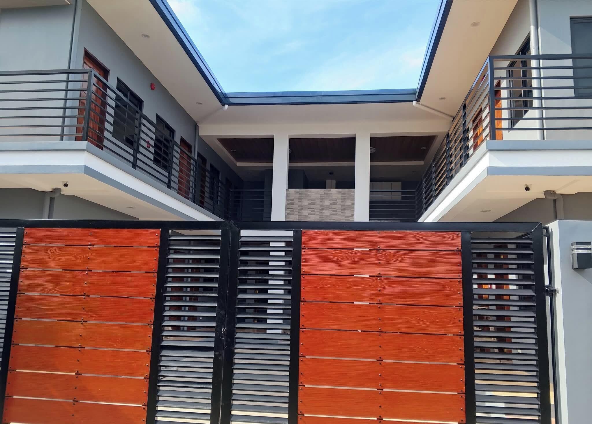 Um edifício moderno com claraboia, área externa coberta e entrada com portão.