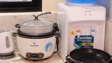 A kitchen with a stovetop, a slow cooker, a water dispenser, and a kettle.