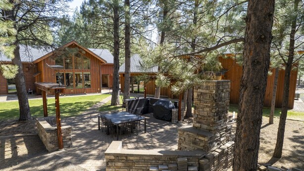 Una cabaña de madera con un área de patio, chimenea de piedra y una mesa de comedor con sillas.