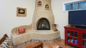 Una sala de estar con chimenea de piedra, televisor y un mueble rojo.