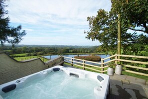 Een jacuzzi met uitzicht op een meer en omliggend groen.