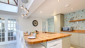 Una cocina moderna con encimera de madera, electrodomésticos blancos y un detalle decorativo en la pared.