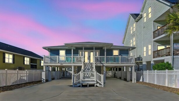 A multi-story hotel with a central staircase, balconies, and a covered walkway. - Shore Beats The Heat- 4BR in Cherry Grove- Pool (North Myrtle Beach)