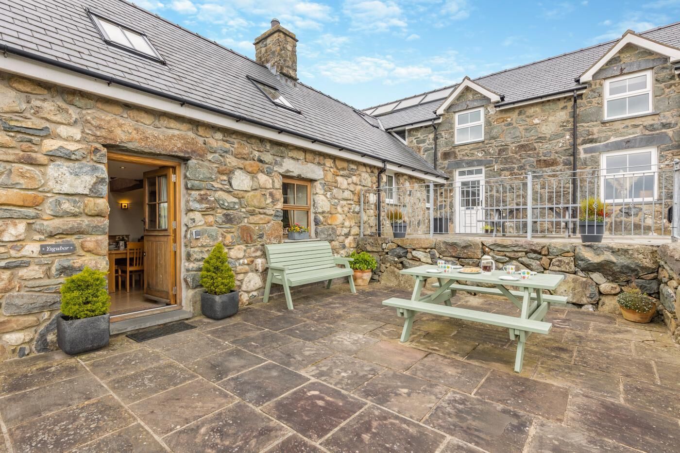 A stone building with a stone facade, a wooden door, a bench, and a picnic table.