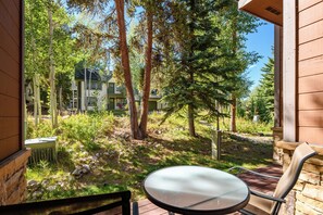 A patio with a table and chairs, surrounded by trees and a building in the background. - Newly Remodeled; Great Location; Heated Garage (Breckenridge)
