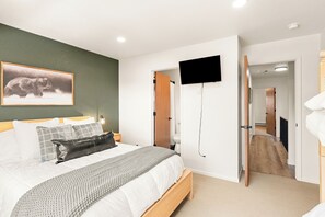 A bedroom with a bed, a mounted TV, and a painting of a bear. - Newly Remodeled; Great Location; Heated Garage (Breckenridge)