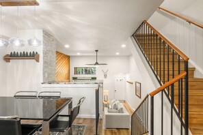 A modern kitchen with a central island, wooden staircase, and a dining area with chairs. - Newly Remodeled; Great Location; Heated Garage (Breckenridge)