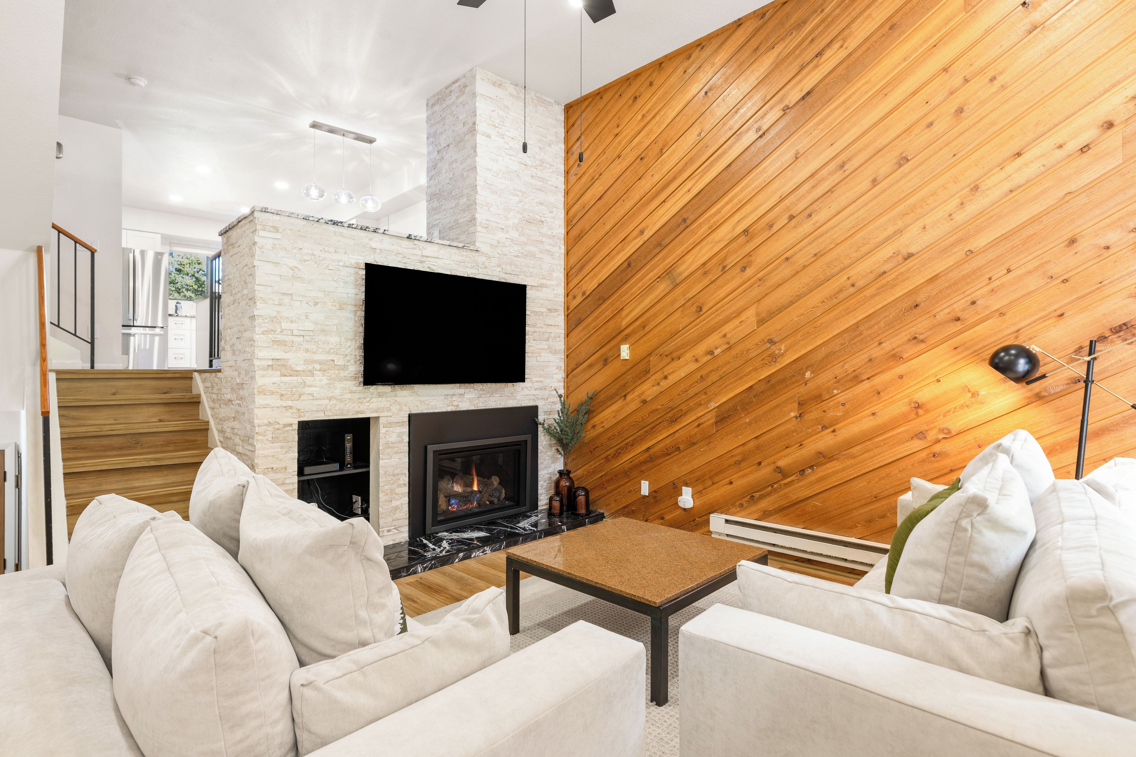 Ein modernes Wohnzimmer mit Kamin, weißem Sofa und einer Wand in Holzoptik.