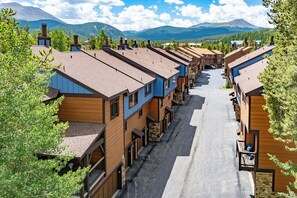 A row of wooden buildings with a central street, surrounded by trees and mountains in the background. - Newly Remodeled; Great Location; Heated Garage (Breckenridge)