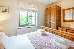 Ein Schlafzimmer mit Bett, einem Fenster mit Blick, einem Holzschrank und einem Heizkörper.