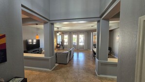 A spacious living area with a large sofa, a dining table, and a TV. - Private Heated pool & Hot tub Oasis! (Goodyear)