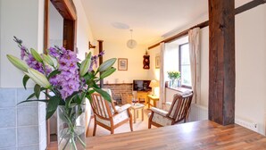 A dining area with a wooden table, chairs, a television, and a fireplace. - 1 Bed in Llanerchymedd (oc-wai212) (Carmel)