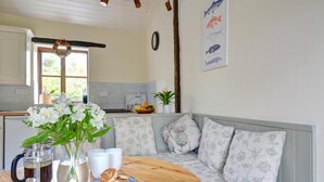 A cozy kitchen with a wooden table, a vase of flowers, a pitcher of coffee, and a plate of pancakes. - 2 Bed in Carmel (oc-wai211) (Carmel)