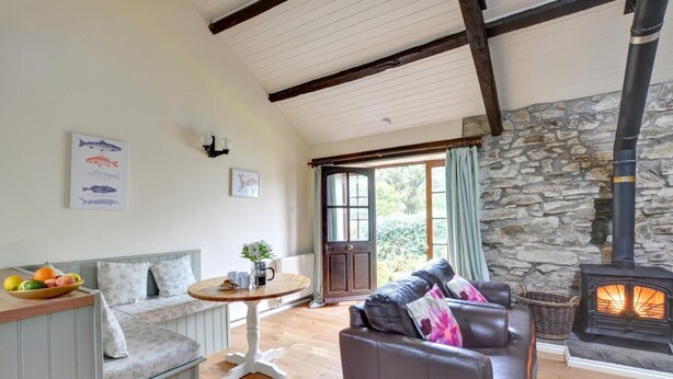 A cozy living room with a stone wall, a fireplace, a sofa, a table with fruit, and a bench. - 2 Bed in Carmel (oc-wai211) (Carmel)