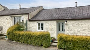A row of stone houses with grey tiled roofs, white doors, and small windows. - 2 Bed in Carmel (oc-wai211) (Carmel)