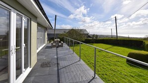 Un balcon donnant sur un espace verdoyant et un paysage lointain.