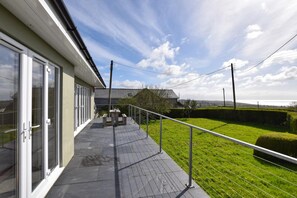 A balcony with a view of a grassy area and a distant landscape. - 3 Bed in Pwllheli (oc-bow04) (Pwllheli)
