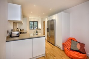Eine moderne Küche mit weißen Schränken, einem eingebauten Backofen und einem Edelstahl-Kühlschrank.