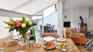 Un comedor con una mesa lista para una comida, un sofá, un televisor y un estufa de leña.