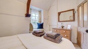 A bedroom with a bed, a dresser, a mirror, and a window.