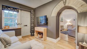 A cozy living room with a sofa, a TV, a console table, and a wooden floor.