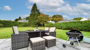 An outdoor patio with wicker furniture, a table, and a grill. - 4 Bed in Llanbedrog (oc-sunnyd) (Llanbedrog)