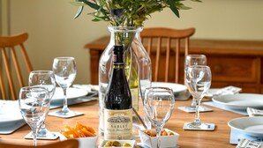 A dining table set with wine glasses, plates, and a vase of flowers. - 4 Bed in Llanbedrog (oc-sunnyd) (Llanbedrog)