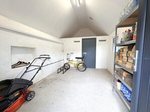 A garage with a lawnmower, a bicycle, and shelves stocked with items. - 3 Bed in Pantglas (oc-bow24) (Pant Glas)