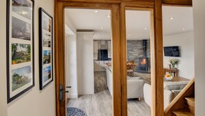 Ein modernes Interieur mit einer Holztür, die in einen Wohn-, Küchen- und Essbereich führt.