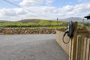 A gravel driveway leading to a wooden fence with a cable reel attached. - 3 Bed in Pantglas (oc-bow24) (Pant Glas)