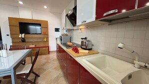 Una cocina moderna con un lavamanos grande, un tostador y un televisor de pantalla plana montado en la pared.